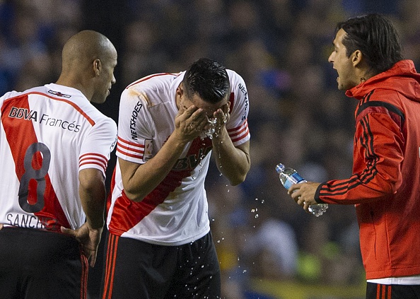 El defensor de River Ramiro Funes Mori (C) se enjuaga los ojos con agua luego de ser agredido con gas pimienta por hinchas de Boca Juniors. (ALEJANDRO PAGNI/AFP/Getty Images)