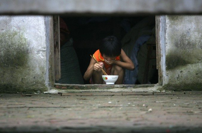 Un niño chino con su cena en la aldea Sanshilipu, condado de Yingshang, provincia de Anhui, en China, el 9 de julio de 2006. (China Photos / Getty Images)