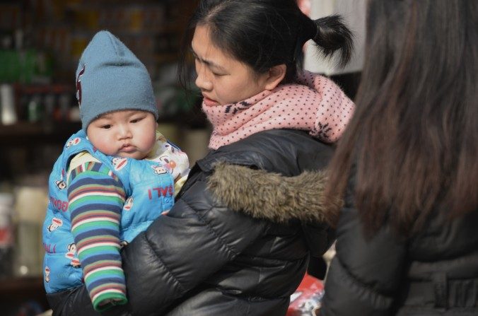 Una madre cargando a su bebé en las calles de Shanghái. (Peter Parks/AFP/Getty Images)