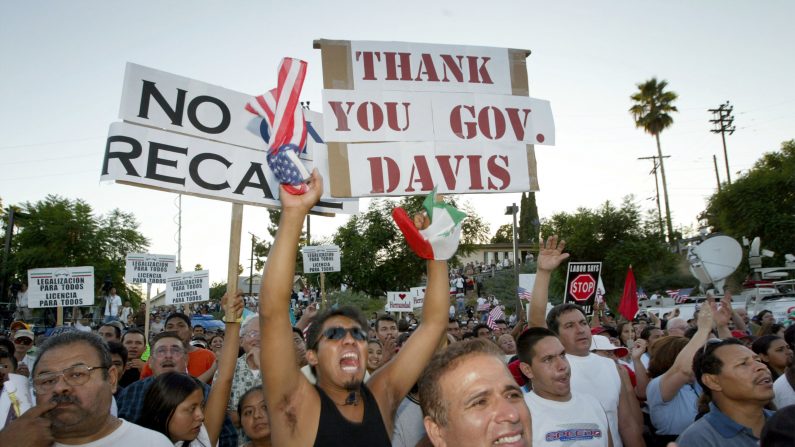 Latinos sostienen un cartel agradeciendo al gobernador de California, Gray Davis por la firma de la ley que permite a los inmigrantes indocumentados obtener una licencia de conducir en California, 5 de septiembre 2003, Los Ángeles, California. (David McNew / Getty Images)