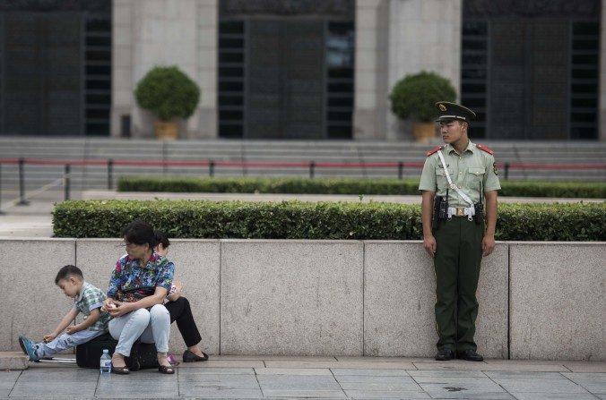 Un guardia paramilitar chino observa a una familia en la Plaza Tiananmen el 01 de septiembre del 2015. (Fred Dufour / AFP / Getty Images)
