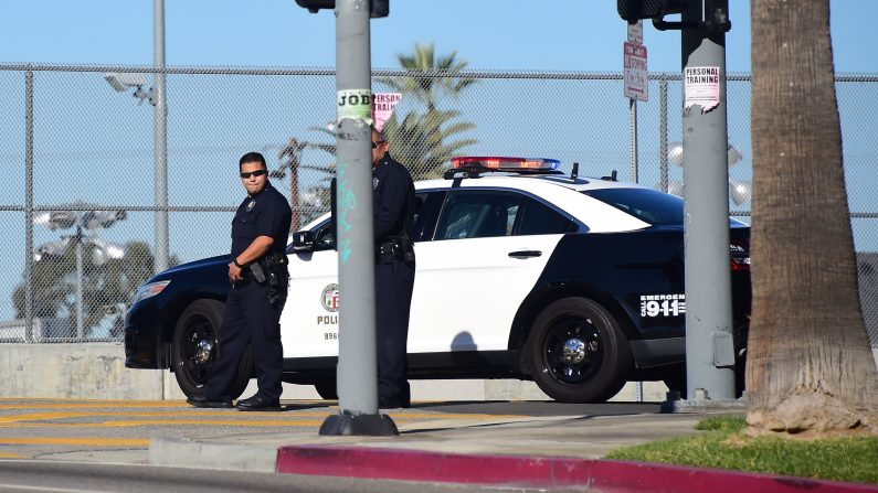 Dos oficiales de policía de pie en su vehículo fuera de una escuela cerrada, cerca del centro de Los Ángeles el 15 de diciembre de 2015 (Frederic J. Brown/AFP/Getty Images)