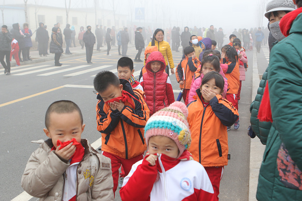 Alumnos cubren sus narices debido a la pesada niebla el 23 de diciembre de 2015 en Binzhou, China. (ChinaFotoPress/ChinaFotoPress via Getty Images)