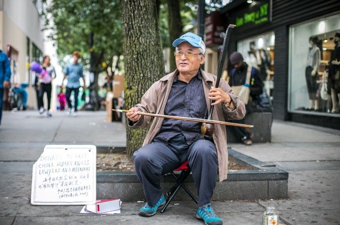 Xin Xiulu toca el erhu en Flushing, Nueva York y acepta donaciones a la gorra para los abogados de derechos humanos detenidos en China, el 29 de septiembre (Benjamin Chasteen/La Gran Época)