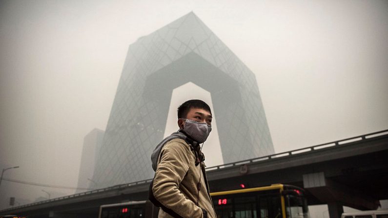 Un hombre chino lleva una máscara mientras espera para cruzar el camino cerca del edificio de CCTV durante smog pesado el 29 de noviembre de 2014 en Beijing, China. (Foto: Kevin Frayer/Getty Images)