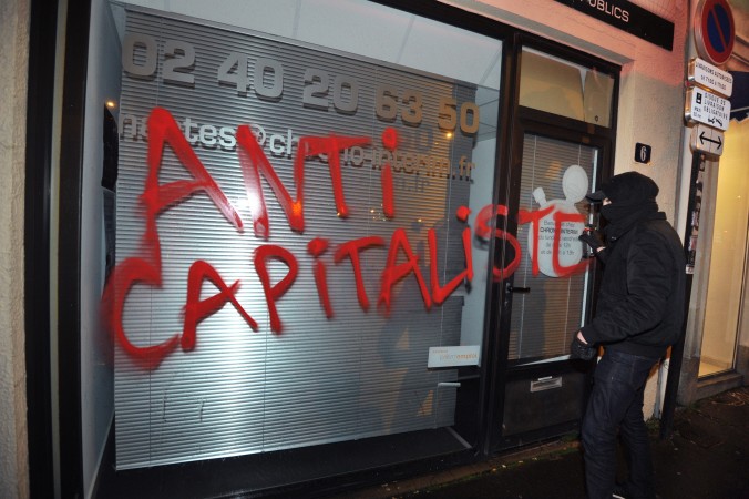 Un miembro del grupo extremista Antifa vandaliza una vidriera en Nantes, Francia, el 14 de febrero de 2014. (FRANK PERRY/AFP/Getty Images)