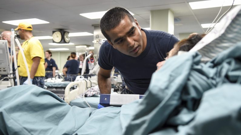 Shiju SantaNivas, enfermero de cuidados intensivos asignado al Centro Médico Militar Nacional Walter Reed, trata a un paciente a bordo del buque hospitalario USNS Comfort, 4 de octubre de 2017. (Foto de U. S. Navy/ Stephane Belcher)