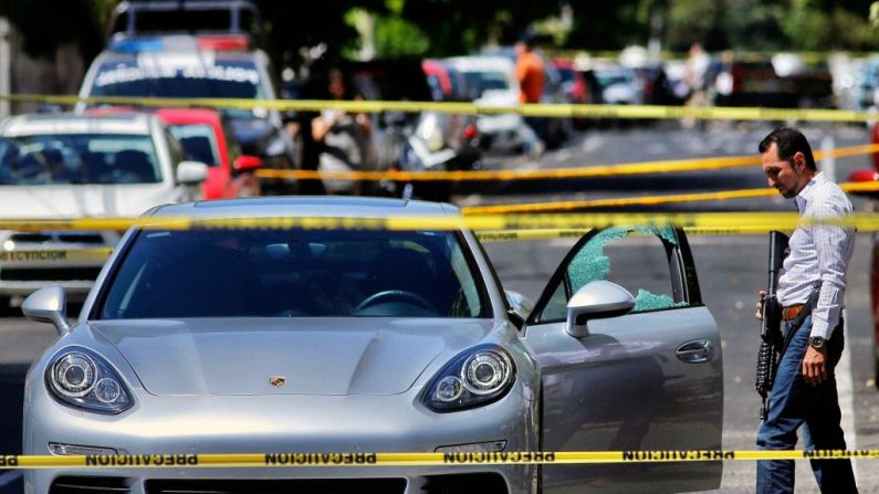 Un miembro de la policía observa el automóvil en el que un hombre fue asesinado a tiros en el barrio Americana, en la zona turística de Guadalajara, estado de Jalisco, México, el 14 de marzo de 2018. (Ulises Ruiz/AFP/Getty Images)