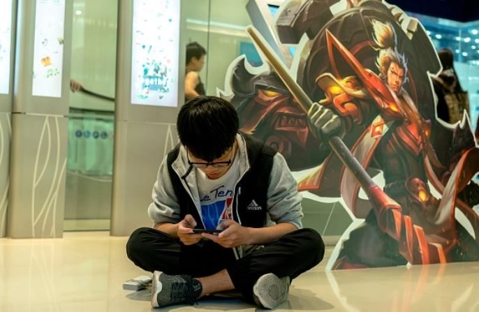 Un joven jugador practica sentado en el pasillo de un centro comercial, donde se disputó una competencia de combate del juego móvil Honor of Kings, en Tianjin, China,  el 1 de octubre de 2017. (Zhang Peng/LightRocket vía Getty Images)