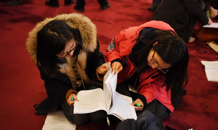 Periodistas chinos analizan una copia del informe de trabajo del gobierno antes de la sesión de apertura del Congreso Nacional Popular, la legislatura garantista del régimen chino, en Beijing el 5 de marzo de 2018. (Greg Baker/AFP/Getty Images)