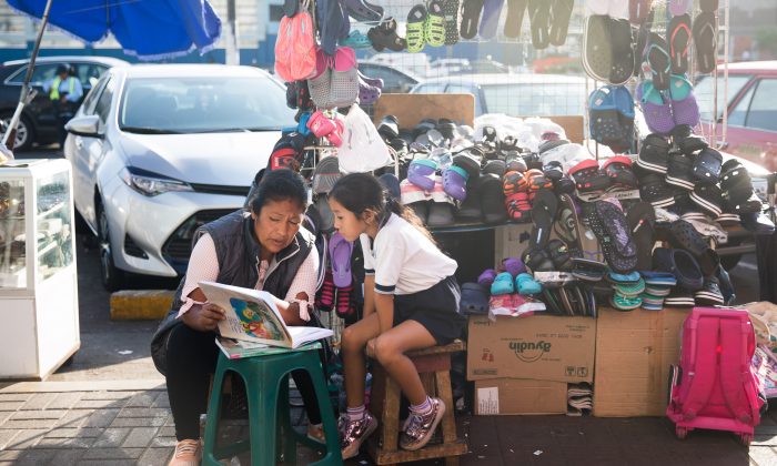 Una mujer lee con un niño cerca del Mercado Surquillo No.1 en Lima, Perú, el 16 de abril de 2018. (Samira Bouaou / La Gran Época)
