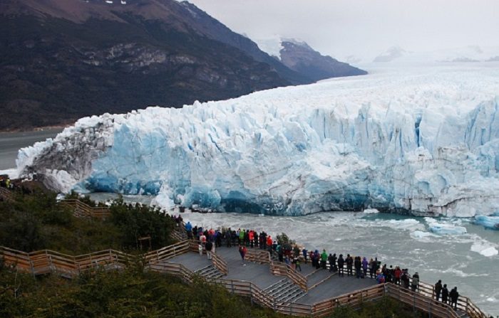 TOPSHOT - Los turistas observan el Glaciar Perito Moreno, en el Parque Nacional Los Glaciares, cerca de El Calafate en la provincia argentina de Santa Cruz, de 2018. Un arco de hielo formado en la punta del Perito Moreno, entre el glaciar y la orilla del lago Argentino, comenzó a desplomarse en el agua el sábado; un despliegue natural que ocurre solo una vez cada varios años. Tales arcos se forman aproximadamente cada dos a cuatro años, cuando el glaciar forma una presa de hielo que corta el flujo de agua a su alrededor hacia el lago - hasta que el agua se rompe, abriendo un túnel cada vez más ancho que finalmente se convierte en un arco estrecho... y luego se derrumba. FOTOGRAFÍA AFP / Walter Díaz (El crédito de la foto debe leer WALTER DIAZ/AFP/Getty Images)