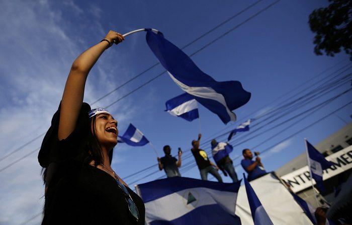 Una joven ondea una bandera nacional durante una protesta hoy, viernes 18 de mayo de 2018, en la ciudad de Managua, (Nicaragua). Cientos de manifestantes marcharon desde centro de Managua hasta la Universidad Centroaméricana de Nicaragua (UCA), exiguiendo la renuncia del presidente electo Daniel Ortega. Al menos 61 personas han fallecido en un mes de protestas contra Ortega en Nicaragua, informó el Centro Nicaragüense de Derechos Humanos (Cenidh). EFE/Bienvenido Velasco