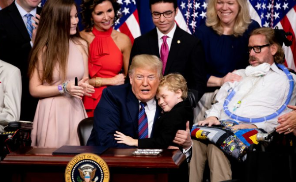 El presidente Donald Trump abraza a un niño con distrofia muscular en la ceremonia de firma de la legislación sobre el "Derecho a Probar" en la Casa Blanca en Washington el 30 de mayo de 2018. (Samira Bouaou / La Gran Época)