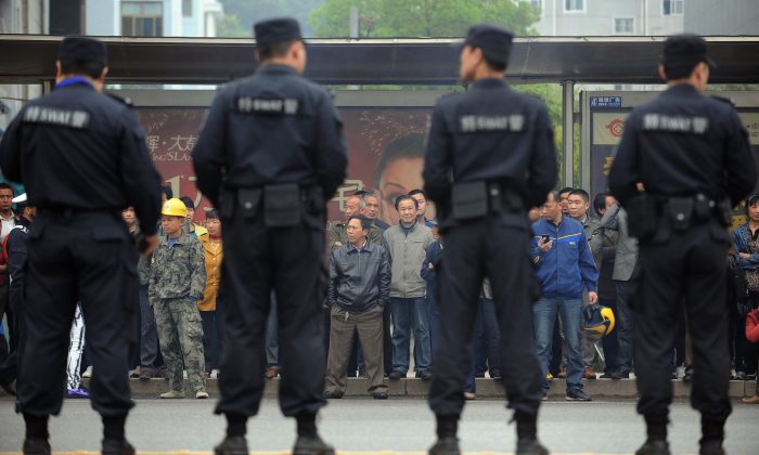 Ciudadanos observan cómo la policía hace guardia frente al Tribunal Popular de Xianning en la ciudad de Xianning, en la provincia central de Hubei, China, el 31 de marzo de 2014. (STR/AFP/Getty Images)