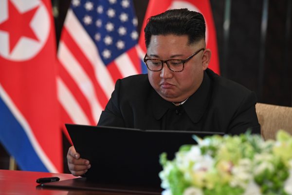 El líder norcoreano Kim Jong-Un lee un documento en una ceremonia de firma con el presidente Donald Trump (no fotografiado) durante su histórica cumbre entre EE. UU., y Corea del Norte en Singapur el 12 de junio de 2018. (SAUL LOEB/AFP/Getty Images)