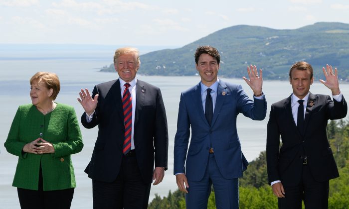La canciller alemana Angela Merkel, el presidente Donald Trump, el primer ministro canadiense Justin Trudeau y el presidente francés Emmanuel Macron saludan durante la foto familiar el primer día de la cumbre del G7 en La Malbaie, Canadá, el 8 de junio de 2018. (Leon Neal / Getty Imágenes)