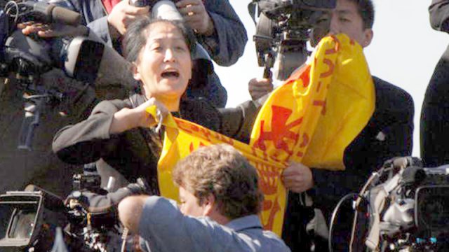 Una mujer (ctro.) interrumpe un discurso del dictador chino Hu Jintao durante una ceremonia de llegada al South Lawn frente a la Casa Blanca el 20 de abril de 2006, en Washington, D.C. (Foto Roger L. Wollenberg-Pool/Getty Images)