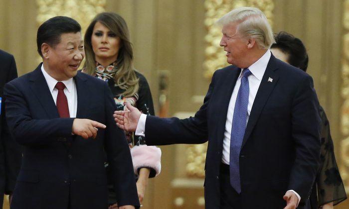 El Presidente de los Estados Unidos, Donald Trump (Der.), habla con el mandatario de China, Xi Jinping, delante de la Primera Dama de Estados Unidos, Melania Trump (2° Izq.), en el momento que llegan para una cena de estado en el Gran Salón del Pueblo en Beijing, el 9 de noviembre de 2017. (THOMAS PETER/AFP/Getty Images)