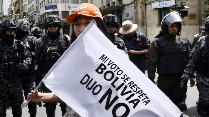 Una joven sostiene una bandera delante de los policías que dice: 'Mi voto debe ser respetado'. Bolivia dijo "No" durante una marcha contra la nominación del presidente boliviano Evo Morales como candidato a la reelección para las elecciones de octubre de 2019, durante un paro nacional, en La Paz, el 6 de diciembre de 2018. (AIZAR RALDES/AFP/Getty Images)