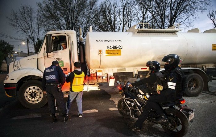 Un camión cisterna que presta servicio a la empresa petrolera mexicana PEMEX sale del centro de distribución vigilado por la policía para distribuir combustible a las gasolineras de la Ciudad de México. Las fuerzas de seguridad mexicanas decomisaron decenas de camiones cisternas usadas para robar combustible. (PEDRO PARDO/AFP/Getty Images)