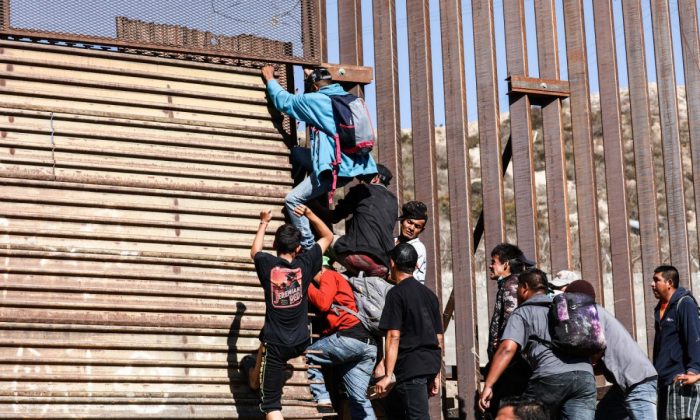 Migrantes se abren camino por la cerca fronteriza de EE. UU. justo donde termina la entrada peatonal este del cruce de San Ysidro en Tijuana, Mexico, el noviembre 25 de 2018. (Charlotte Cuthbertson/La Gran Época)