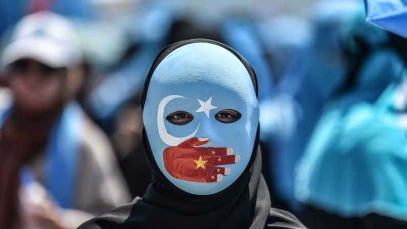 Un manifestante con una máscara pintada con los colores de la bandera de Turquestán Oriental y una mano con los colores de la bandera china asiste a una protesta de los partidarios de la minoría uigur, en su mayoría musulmana, y de los nacionalistas turcos para denunciar el trato de China a los musulmanes de etnia uigur durante un motín mortal que tuvo lugar en julio de 2009 en Urumqi, frente al consulado chino en Estambul, el 5 de julio de 2018. (OZAN KOSE / AFP) (Crédito de la foto: OZAN KOSE/AFP/Getty Images)
