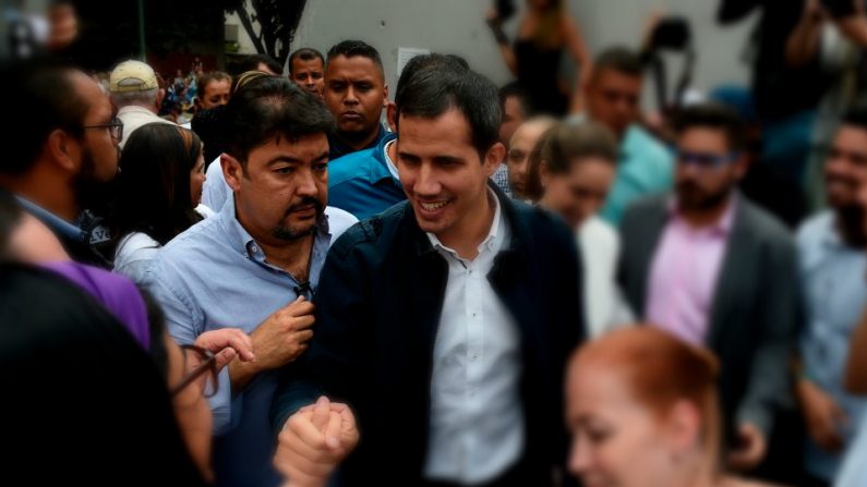 Roberto Marrero (izq.), mano derecha y jefe de despacho del presidente encargado venezolano Juan Guaido (C), saludan a sus seguidores durante un mitin en Caracas el 8 de marzo de 2019. (FEDERICO PARRA/AFP/Getty Images)