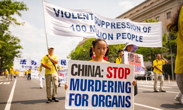 Una joven practicante de Falun Dafa sostiene un cartel que pide a China que deje de matar a prisioneros de conciencia por sus órganos en un desfile en Washington, el 20 de julio de 2017. (Benjamin Chasteen/La Gran Época)