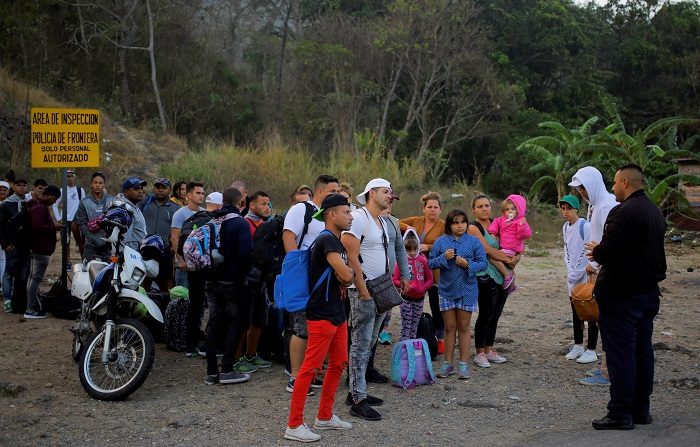 Migrantes cubanos hablan con un agente de migración este viernes al llegar a la Aduana de Agua Caliente (Honduras), fronterizo con Guatemala. En este punto fronterizo se encuentra una caravana migrante convocada por redes sociales y que salió el martes de San Pedro Sula, en el norte hondureño. EFE/ Gustavo Amador