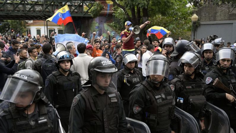 La policía antidisturbios de Argentina forma un cordón entre los partidarios venezolanos del presidente encargado de Venezuela, Juan Guaido, y los que apoyan al régimen de Nicolás Maduro, reunidos frente a la embajada de Venezuela en Buenos Aires durante una manifestación el 30 de abril de 2019. (JUAN MABROMATA/AFP/Getty Images)