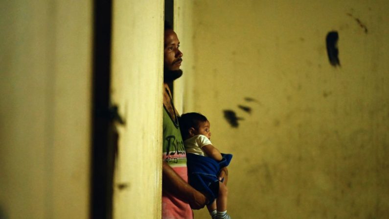 El venezolano Eymir Aponte sostiene a uno de sus hijos en el refugio Jehova Gire, un edificio a medio hacer del poder judicial en el barrio de Petare, Caracas, el 19 de mayo de 2019. Símbolo de la ocupación ilegal desde la época del difunto líder socialista Hugo Chávez (1999-2013), el esqueleto de hormigón es el hogar de indigentes, víctimas de desastres y otros que cayeron en desgracia con la peor crisis económica en la historia reciente del país productor de petróleo. (MARVIN RECINOS/AFP/Getty Images)
