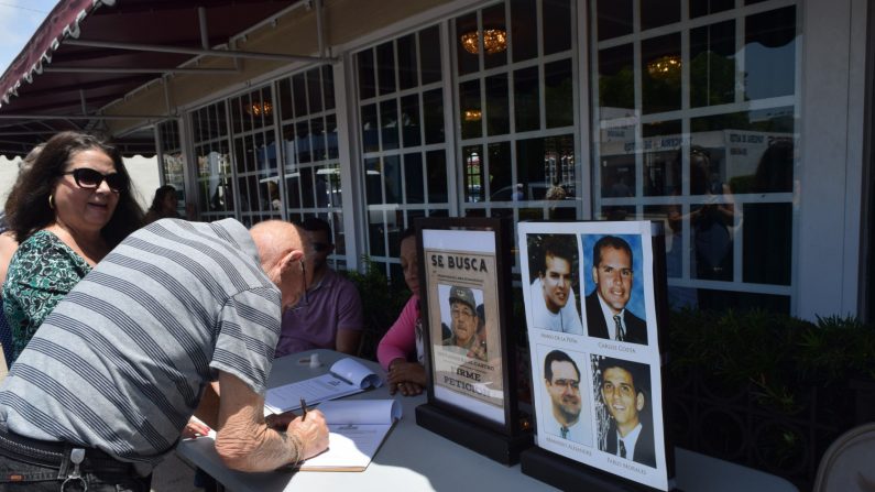 Una persona firma un libro con la petición de juzgar a Raúl Castro este jueves, en el exterior del emblemático restaurante Versailles, en Miami, Florida (EE.UU.). EFE
