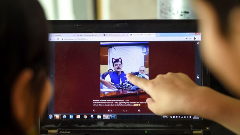 Niños pakistaníes señalan la pantalla de una notebook que muestra una captura de pantalla de una conferencia de prensa a la que asistió el ministro provincial Shaukat Yousafzai y que fue transmitida en vivo por los medios sociales, en Islamabad, el 15 de junio de 2019. (FAROOOQ NAEEM/AFP/Getty Images)