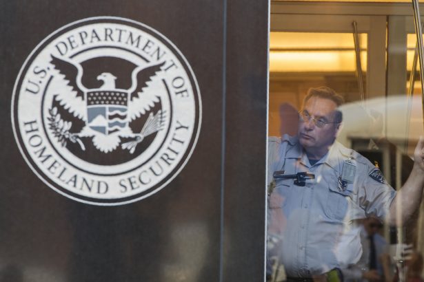 Un oficial de seguridad mira por una ventana en la oficina del Servicio de Inmigración y Control de Aduanas de Estados Unidos (ICE), parte del Departamento de Seguridad Nacional (DHS), en Washington el 4 de octubre de 2017. (Andrew Caballero-Reynolds/Getty Images)