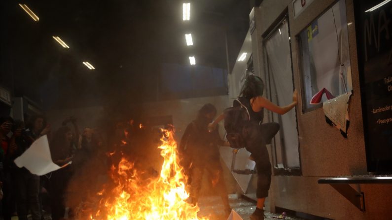 Feministas rompen vidrios y queman papeles al interior de un edificio durante una marcha el 16 de agosto en Ciudad de México, México. (Sashenka Gutiérrez/EFE)
