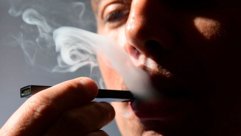 Una ilustración muestra a un hombre exhalando humo de un cigarrillo electrónico en Washington, DC, el 2 de octubre de 2018. En solo tres años, estos cigarrillos se han difundido en el mercado estadounidense pero su éxito representa un dilema de salud pública para las autoridades de salud en Estados Unidos y en otros lugares. (EVA HAMBACH / AFP / Getty Images)