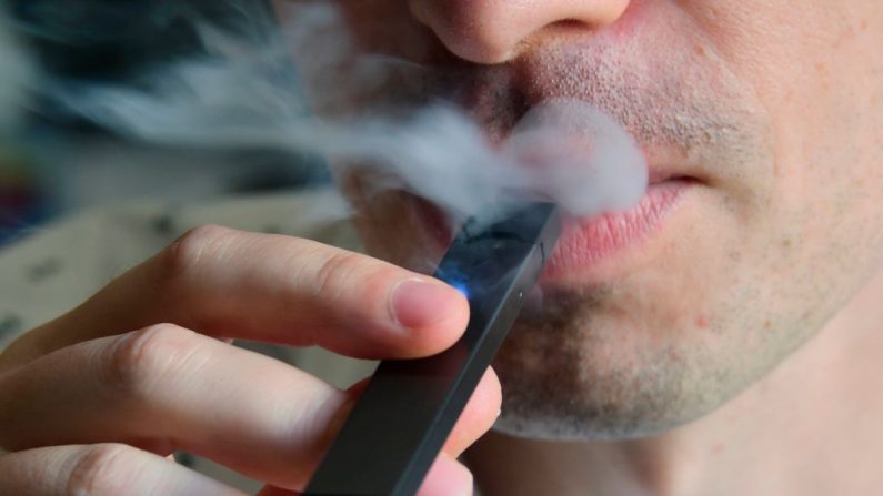 Una ilustración muestra a un hombre exhalando humo de un cigarrillo electrónico. (Eva Hambach/Getty Images)