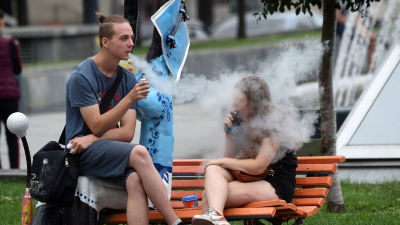 Dos jóvenes fuman cigarrillos electrónicos en el centro de la capital ucraniana de Kiev, el 15 de agosto de 2019. (SERGEI SUPINSKY/AFP/Getty Images)