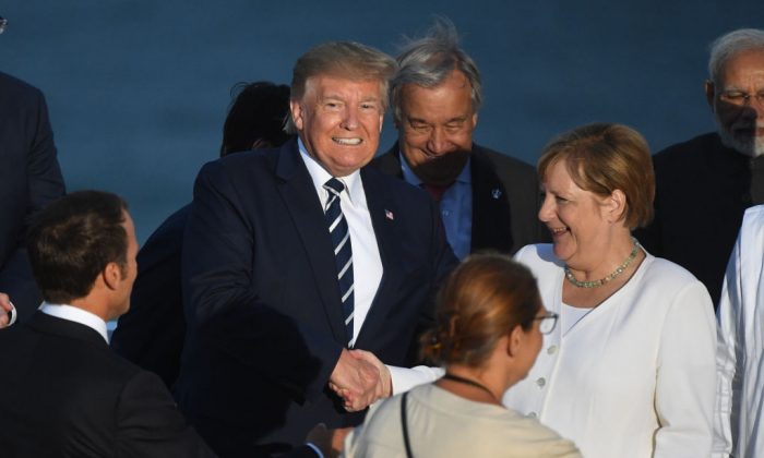 El presidente de Estados Unidos, Donald Trump, saluda a la canciller alemana Angela Merkel mientras los líderes del G7 y sus invitados se reúnen para una foto frente al faro de Biarritz en el segundo día de la cumbre anual del G7 en Biarritz, Francia, el 25 de agosto de 2019. (Andrew Parsons - Pool/Getty Images)