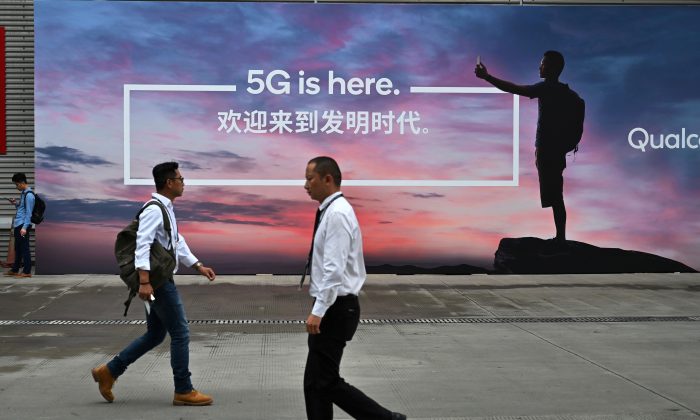 Personas pasando por delante de un cartel publicitario de la tecnología 5G de Internet en el Congreso Mundial Móvil (MWC 2019) que presenta tecnología de última generación en el Nuevo Centro de Exposición de Shanghai en Shanghai, el 26 de junio de 2019. (Hector Retamal/AFP/Getty Images)