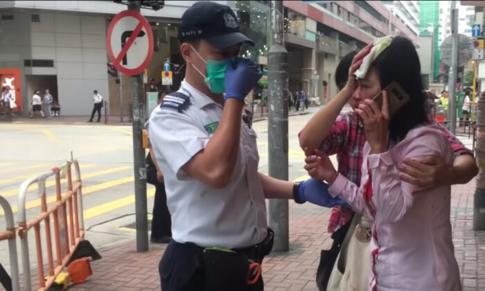 Liao Qiulan fala com um policial depois de ter sido atacada por um homem com um bastão em Hong Kong, em 24 de setembro de 2019 (The Epoch Times)