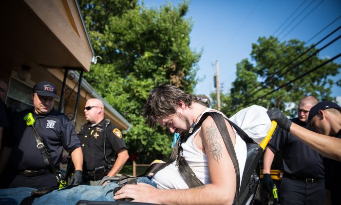 A polícia local, o corpo de bombeiros e os xerifes ajudam um homem que havia ingerido uma overdose no bairro de Drexel em Dayton, Ohio, em 3 de agosto de 2017 (Benjamin Chasteen / The Epoch Times)