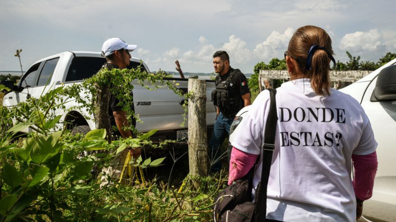 Familiares de desaparecidos hablan con un policía el 17 de septiembre de 2018, a la entrada del lugar donde se encontró una fosa común en El Arbolillo, municipio de Alvarado, en el estado mexicano de Veracruz, una región azotada por sangrientas guerras entre cárteles de drogas. (Victoria Razo/AFP/Getty Images)