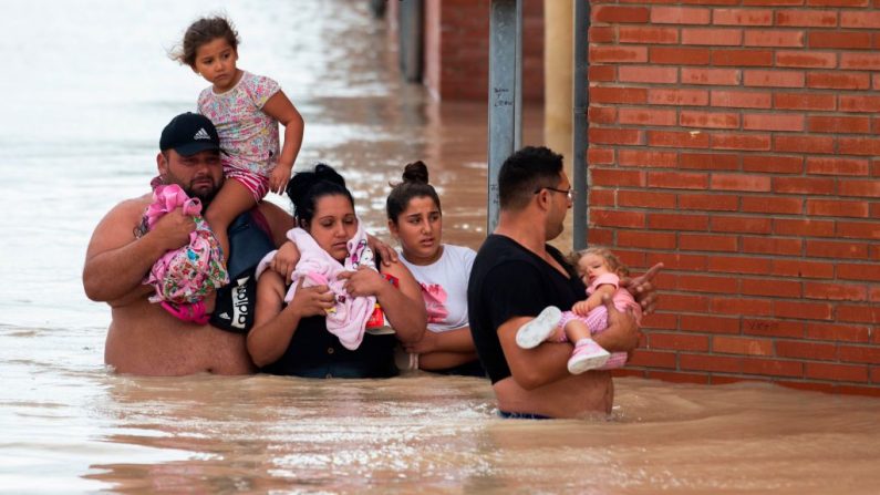 La gente lleva a los niños a una calle inundada en Almoradí el 13 de septiembre de 2019. La tormenta causó estragos en los viajeros y obligó a 3.500 personas a abandonar sus hogares. (JOSE JORDAN / AFP / Getty Images)