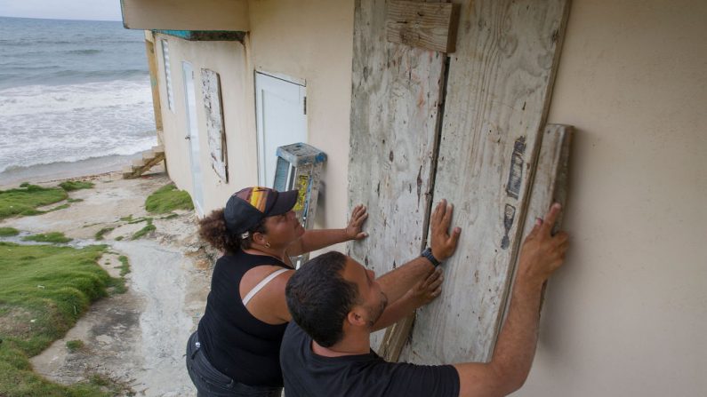 Ya Mary Morales (izq.) y Henry Sustache ponen madera sobre las ventanas de su casa mientras se preparan para la llegada de la tormenta tropical Dorian el 28 de agosto de 2019 a Yabucoa, Puerto Rico. (Joe Raedle/Getty Images)

