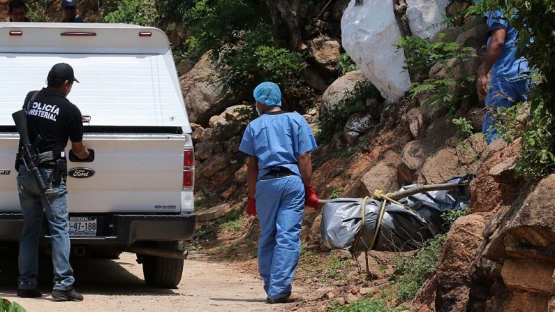 Personal forense carga en una camioneta el cuerpo de uno de los diez cadáveres encontrados en fosas clandestinas en la turística ciudad de Acapulco, estado de Guerrero, el 22 de junio de 2015. Guerrero es uno de los estados más pobres y violentos de México, donde ha florecido un lucrativo tráfico de drogas. (STR/AFP/Getty Images)
