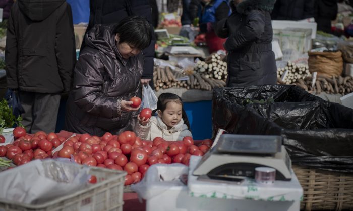 Una niña ayuda a una mujer a elegir tomates en un mercado de Beijing, el 27 de febrero de 2019. (Nicolas Asfouri/ AFP/Getty Images)