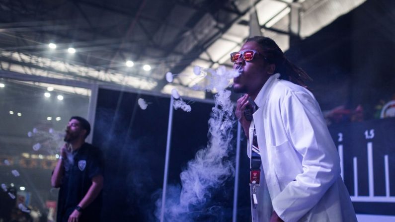 Dois homens sopram fumaça de cigarros eletrônicos para fazer truques no ar enquanto se apresentam em um palco em Pretória, África do Sul, em 1º de setembro de 2019 (GUILLEM SARTORIO / AFP / Getty Images)