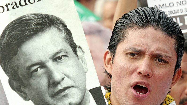 Uma pessoa mostra um cartaz do prefeito da Cidade do México, Andrés Manuel López Obrador, do Partido da Revolução Democrática, durante uma reunião em El Zócalo, o principal local da capital, em 7 de abril de 2005. Ele foi acusado por parlamentares de desobedecer a um tribunal (JUAN BARRETO / AFP / Getty Images)